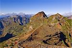 Hiker in red jacket walking down new footpath across the volcanic landscape towards Madeira's third highest peak, Pico do Arieiro, Madeira, Portugal, Europe