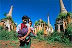 Young girl carrying a baby on her back in front of the ancient stupas at the Indein archaeological site, Inle Lake, Shan State, Myanmar (Burma), Asia