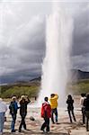 Touristes regardant le Geyser de Strokkur en éruption, Geysir, Islande, régions polaires