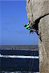 A climber tackles a difficult overhang on the cliffs near Sennen Cove, a popular rock climbing area at Lands End, Cornwall, England, United Kingdom, Europe
