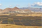 View across black volcanic cinder fields to the town of Soo and the Risco de Famara range with the highest point on the island at Penas del Cache radar site, Soo, Lanzarote, Canary Islands, Spain, Atlantic Ocean, Europe