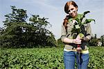 Young woman holding fresh beetroot in field