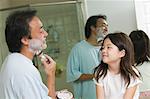 Daughter watching father apply shaving cream in bathroom