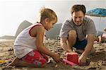 Père et fils, jouant dans le sable à la plage