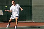 Tennis Player swinging tennis racket in forehand motion on tennis court
