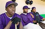 Baseball players sitting in dugout, (portrait)