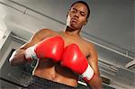 Boxer with red boxing gloves in gym, half length