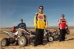 Men standing by quad bikes in desert