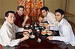 Young men eating sushi with chopsticks in restaurant