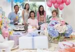 Woman sitting at baby shower behind table of gifts
