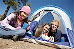 Three young adults at campsite by tent at campsite