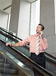 Businessman using mobile phone on escalator