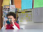 Boy drinking from cup in classroom