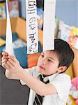 Elementary schoolboy learning to read from hanging paper strip in classroom, elevated view