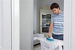 Man ironing shirt in living room