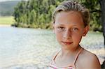 Girl (7-9) standing by lake, portrait.