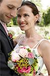 Mid adult bride and groom holding bouquet, smiling