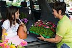 Grandmother and granddaughter loading flowers into back of SUV