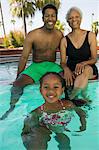 Girl (5-6) with father and grandmother at swimming pool, portrait.