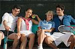 Les joueurs de tennis double mixte quatre assis sur un banc au court de tennis, portrait