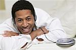 Man lying on sofa Listening to Music on portable CD player, portrait