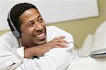 Man lying on sofa Listening to Music on portable CD player, close up, front view