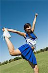 Teenage Cheerleader stretching on lawn