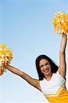 Smiling Cheerleader rising pom-poms, (portrait)