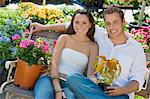 Young couple sitting on bench in garden centre, (portrait)