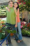 Woman embracing man with pushcart in garden centre, (portrait)