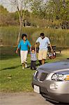 Family walking by river behind car