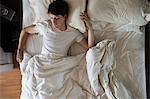 Man sleeping alone in double bed