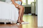 Legs of woman on bed with tissues on floor