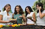Four women around outdoor grill.
