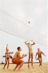 Femme sautant de volley-ball au cours du jeu sur la plage