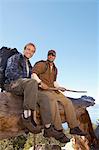 Two male hikers sitting on log, (portrait)