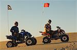 Men sitting on quad bikes in desert