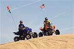 Young Men Riding ATVs Over Sand Dunes