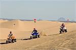 Three Young Men Riding ATVs on Dunes