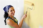 Woman applying yellow paint to interior wall, elevated view