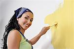 Woman painting interior wall, low-angle view, portrait