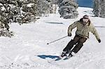 Young Man Skiing down snow covered slope, full length