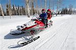 Couple driving snowmobile on snow covered track