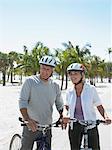 Couple senior à bicyclette sur une plage tropicale