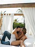 Mid-adult couple kissing on bed outside