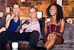 Man with two women sitting on couch in bar