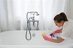 Young woman cleaning bathtub