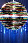 Multi-coloured disco ball in front of blue stage curtain, close up