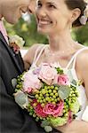 Mid adult bride and groom in garden, smiling, close-up