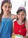 Portrait of two girls (7-9, 10-12) in tiaras, smiling